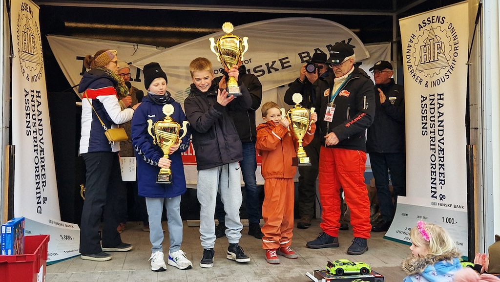 Vinderne af de tre aldersgrupper i moon-car racet hæver deres pokaler højt på scenen efter præmieoverrækkelsen.
(Foto: rallypics.dk – Viggo Johansen)